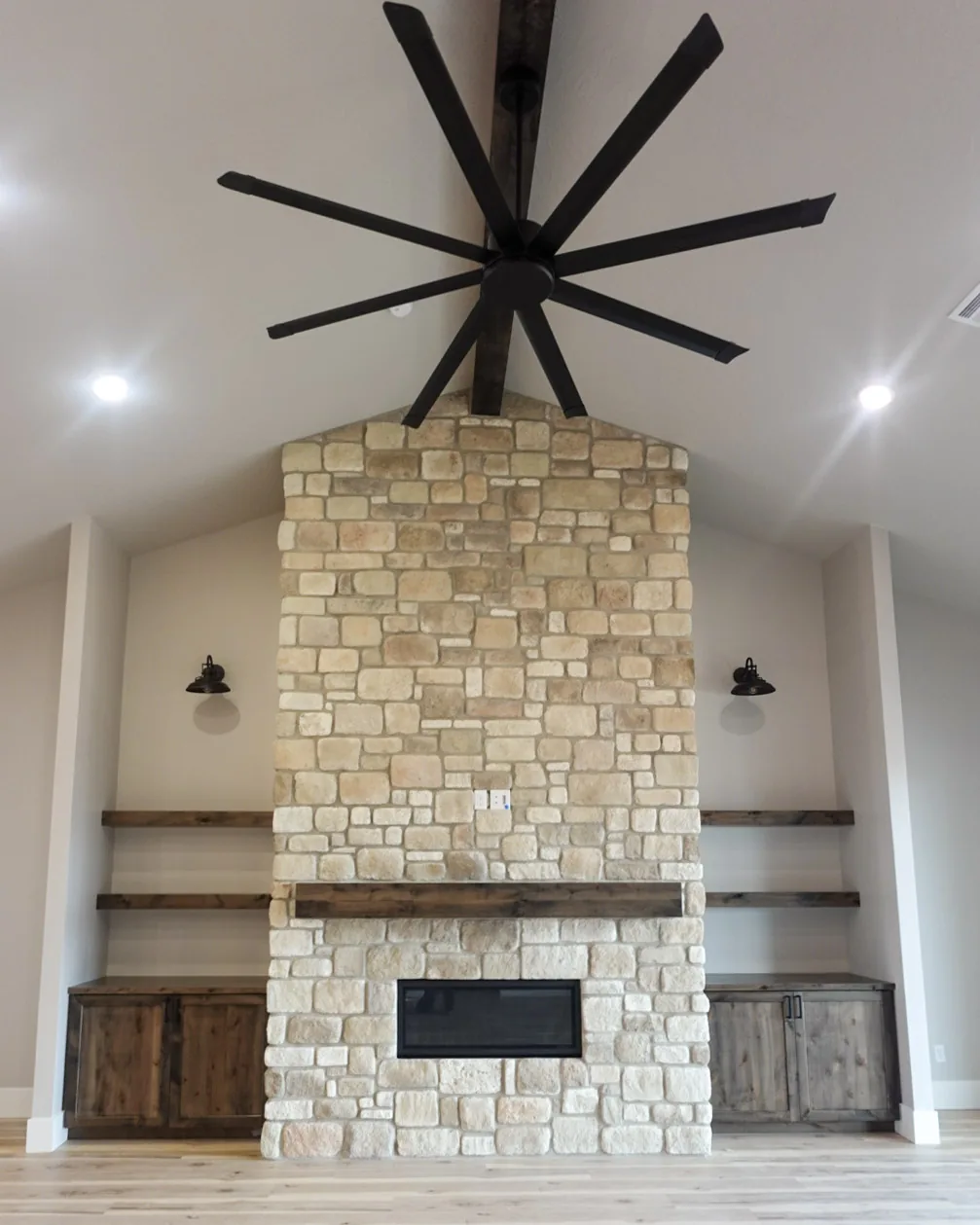 Floor-to-ceiling stone fireplace with a timber mantel and flanking built-ins