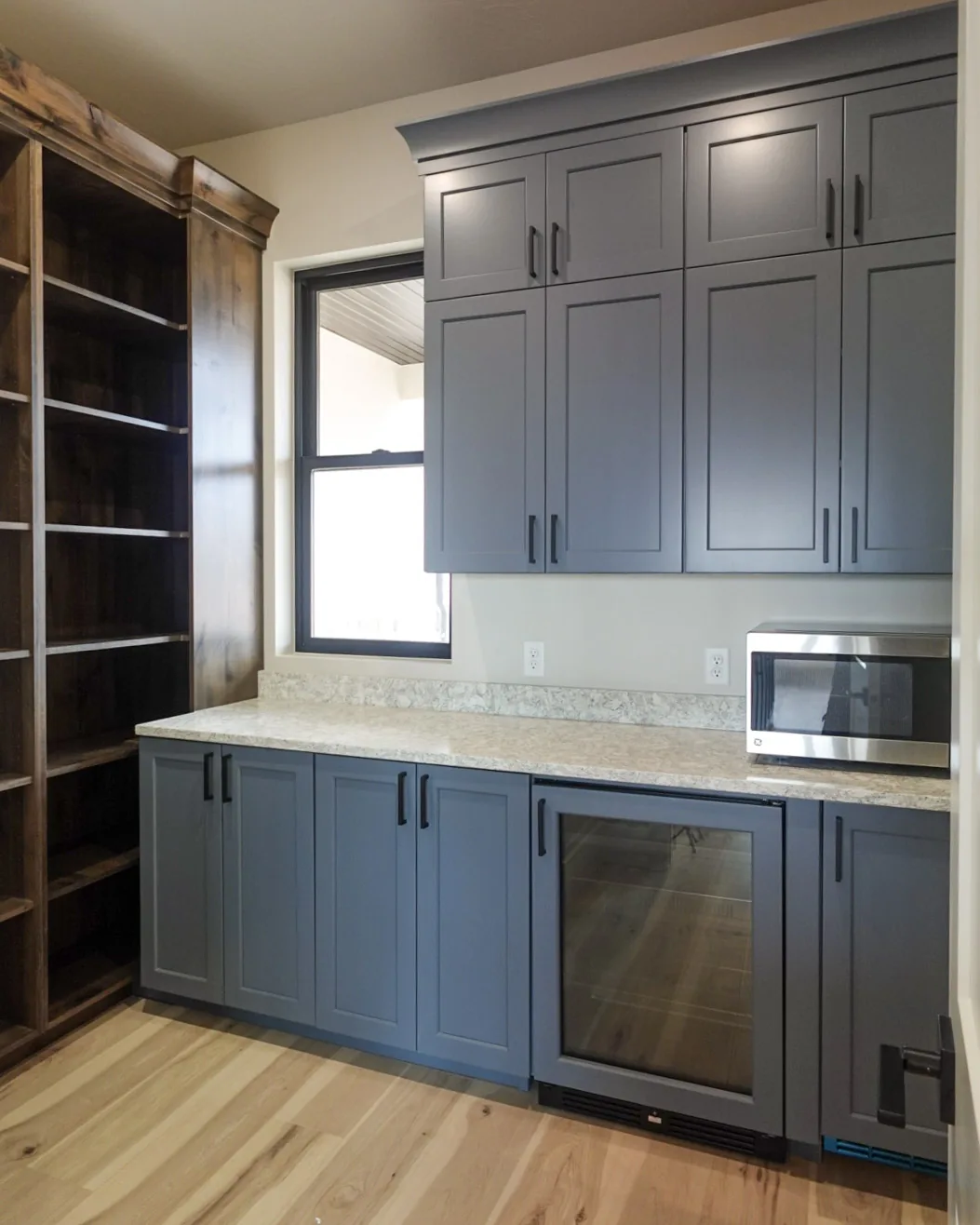 Butler's pantry with navy cabinetry, a beverage fridge, and open shelving