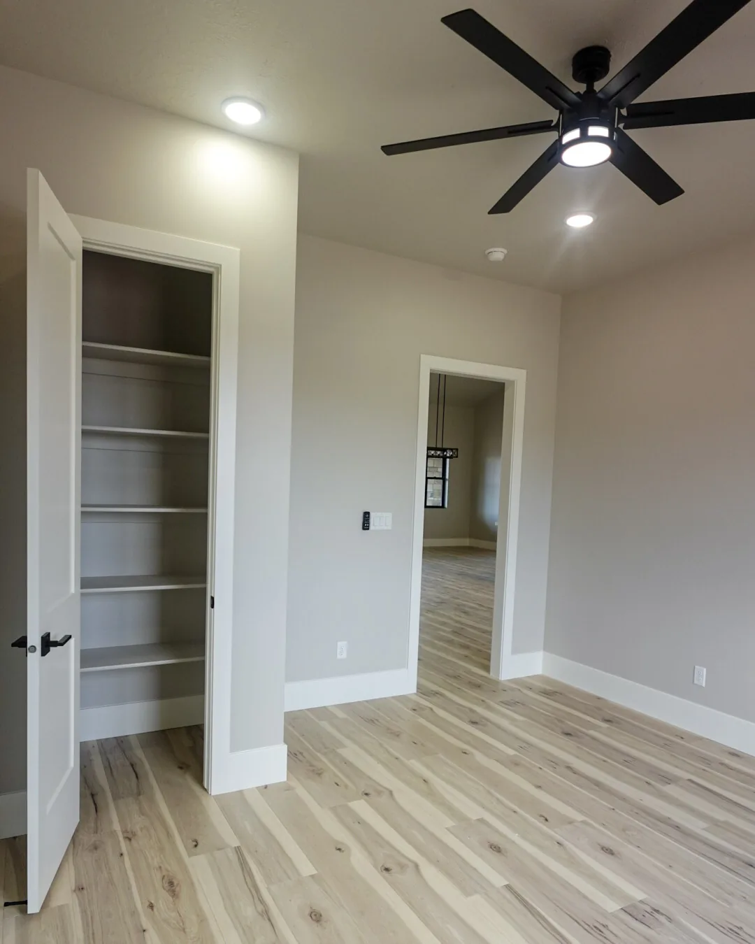 Hallway with a built-in linen closet and wide plank flooring