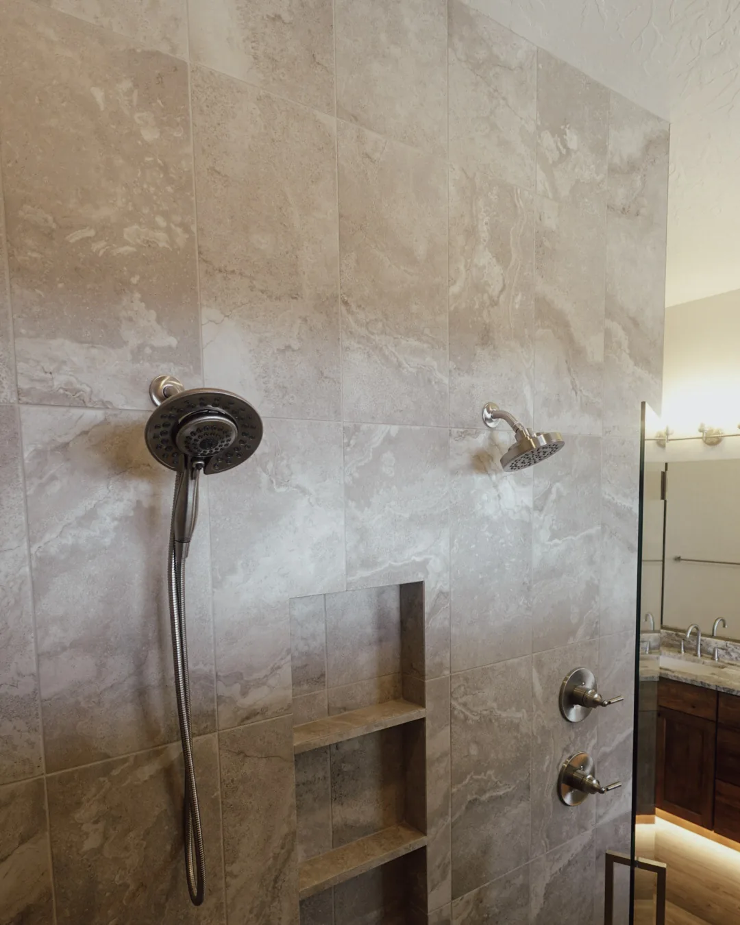 Large-format tiled shower with dual heads and a built-in niche