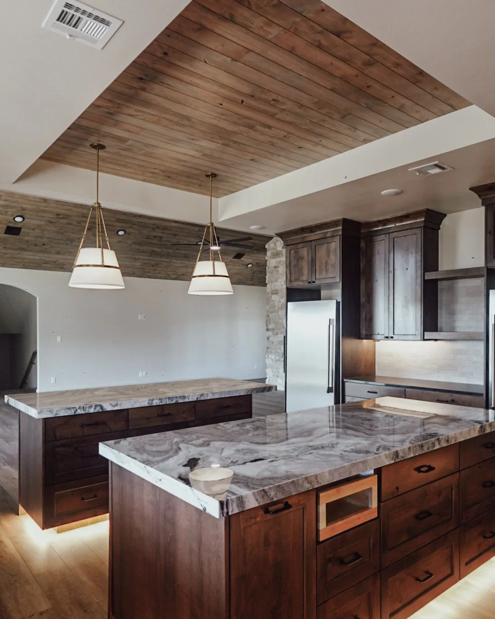 Kitchen island in stone with knotty alder cabinetry and a built-in microwave