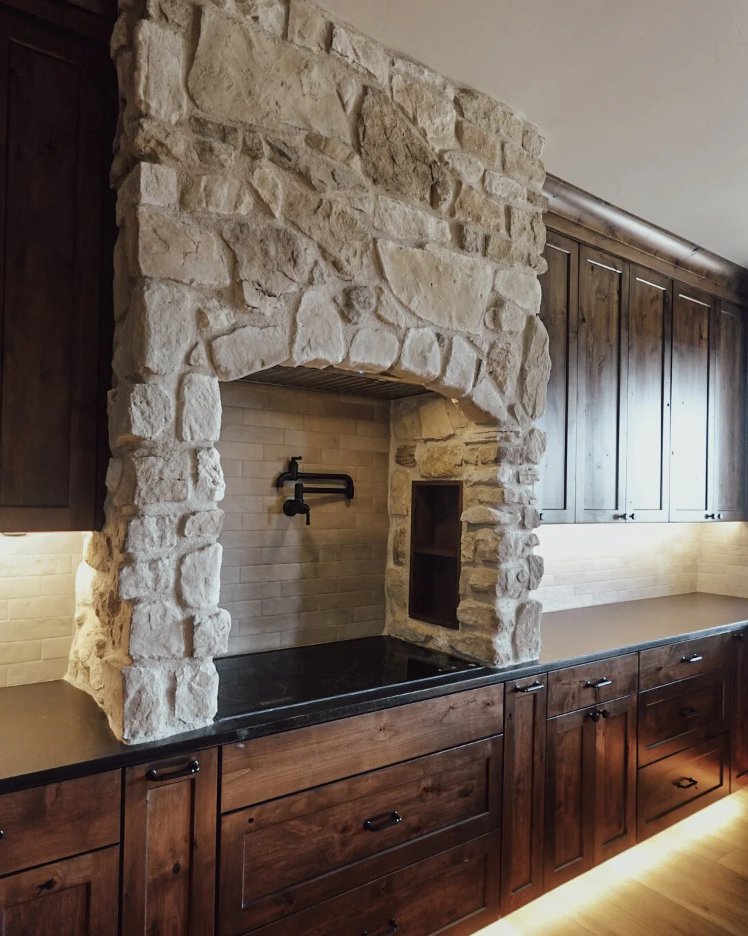 Hand-set stone range arch with a pot filler above the cooktop