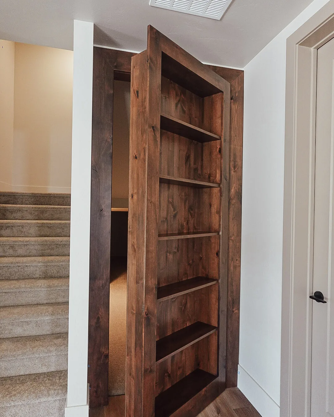 Bookshelf door standing open onto a hidden staircase