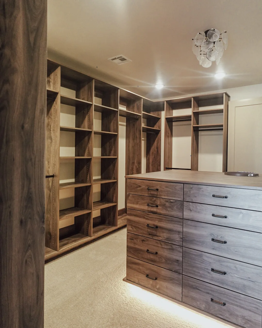 Walk-in closet with custom shelving, hanging space, and a drawer island